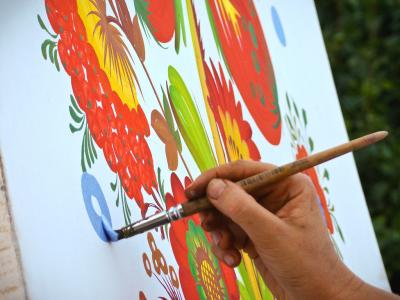 Рука художника выполняет петриковскую роспись